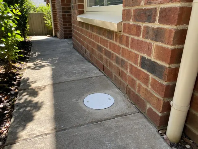 Brick house side path with a flush circular inspection cap beside a wall in Pymble